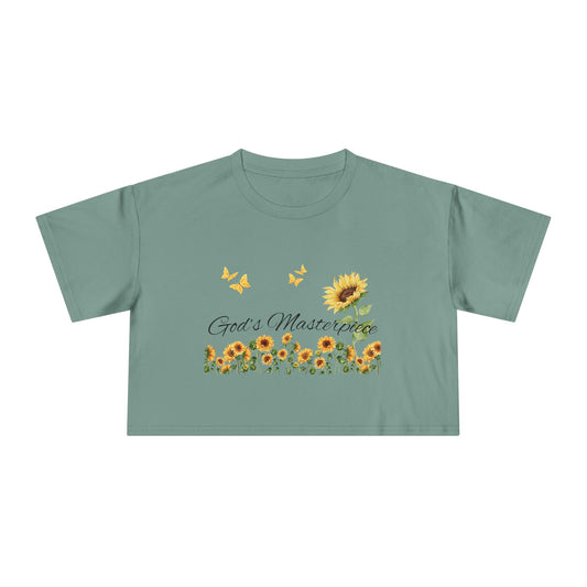 Christ Centered Faith women's cropped Christian t-shirt with "God's Masterpiece" text in black surrounded by sunflowers and yellow butterflies on green background.