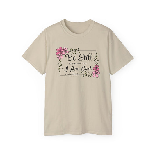 Christ Centered Faith women's Christian t-shirt with "Be Still And Know That I Am God" and Psalm 46:10 Bible Verse text in black with pink flowers and green vine on beige background.