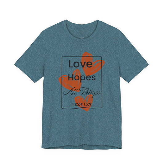Christ Centered Faith women's Christian t-shirt with "Love Hopes All Things" and 1 Corinthians 13:7 Bible verse text in black over red hearts inside a black rectangle outline on blue background.