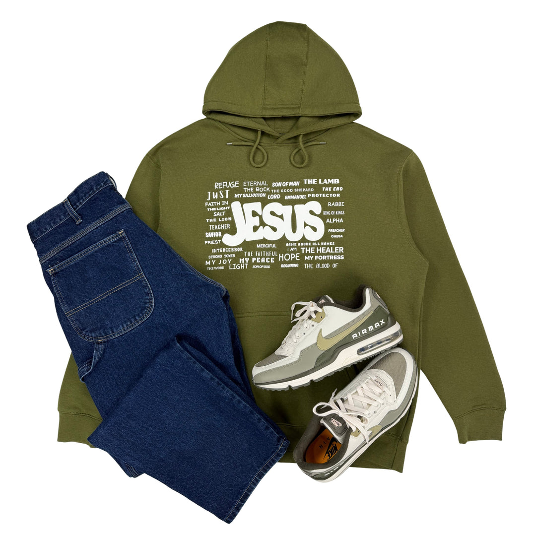 Military green Christian hoodie featuring the names of Jesus styled with blue jeans and sneakers on a white background.